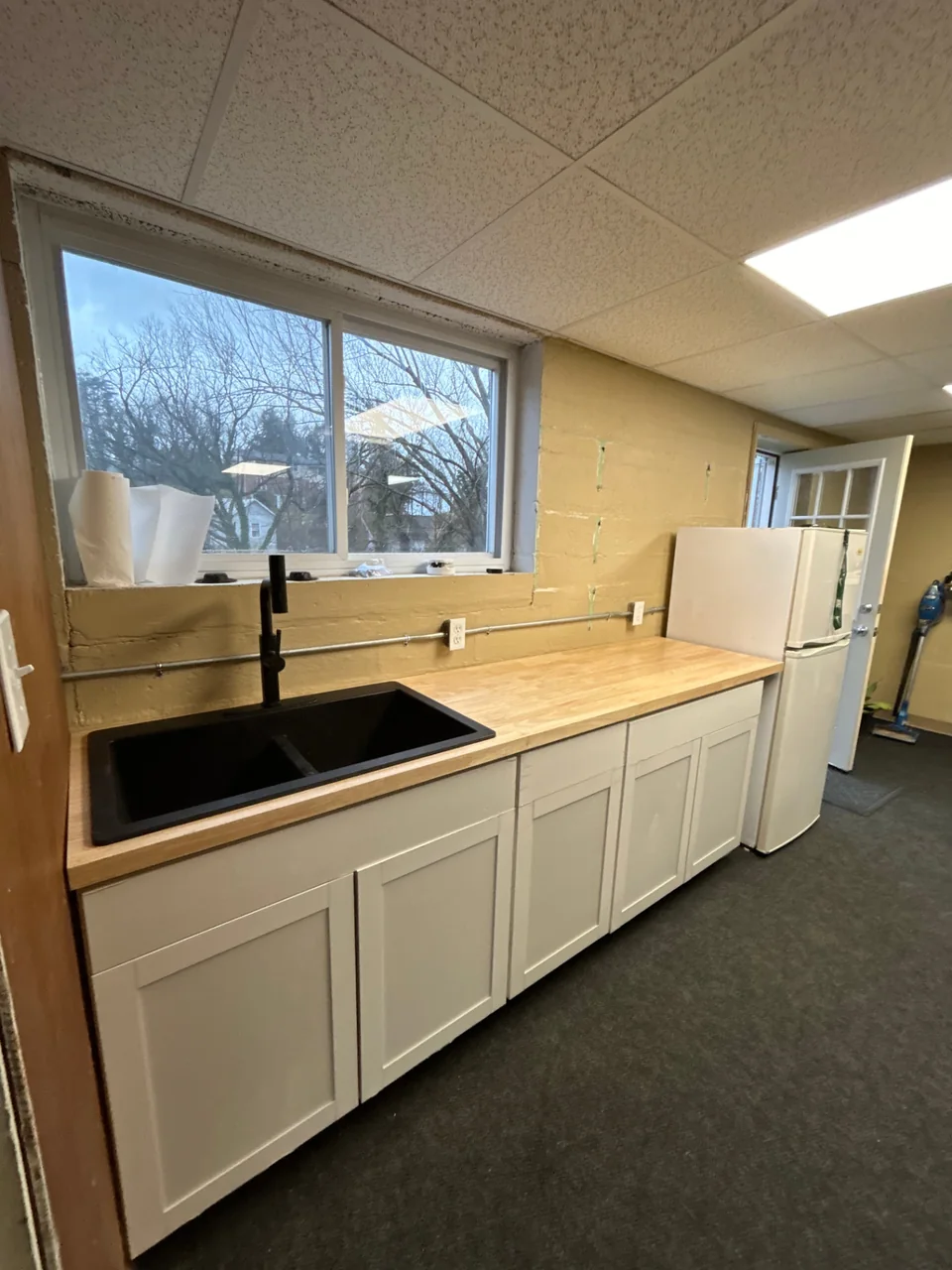 White cabinets with butcher-block counters and a black granite sink.