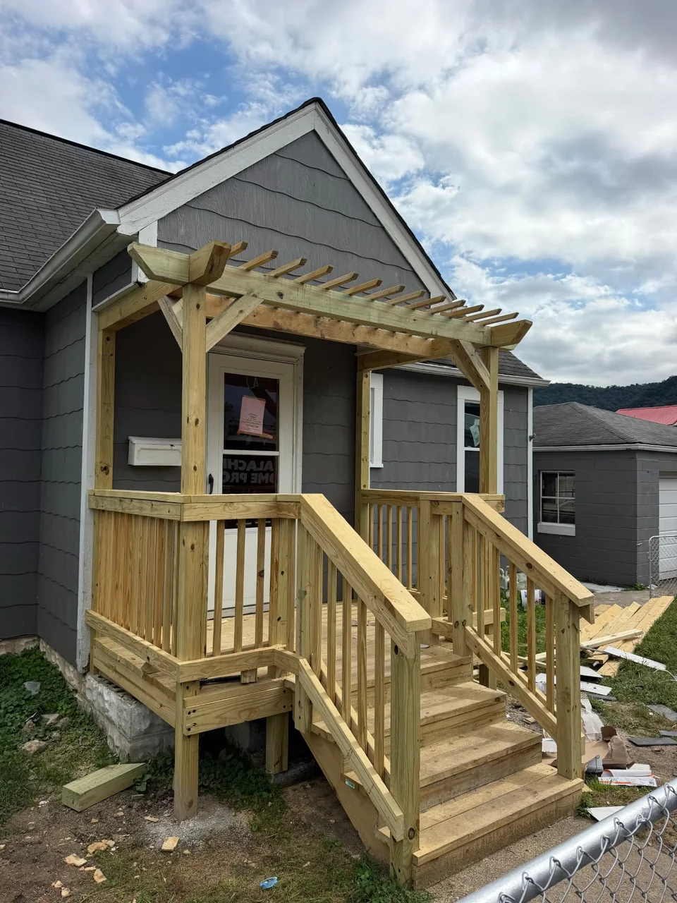 Wood steps, railings and an overhead pergola.